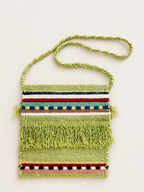 Green woven bag with colorful stripes and fringes on a light background