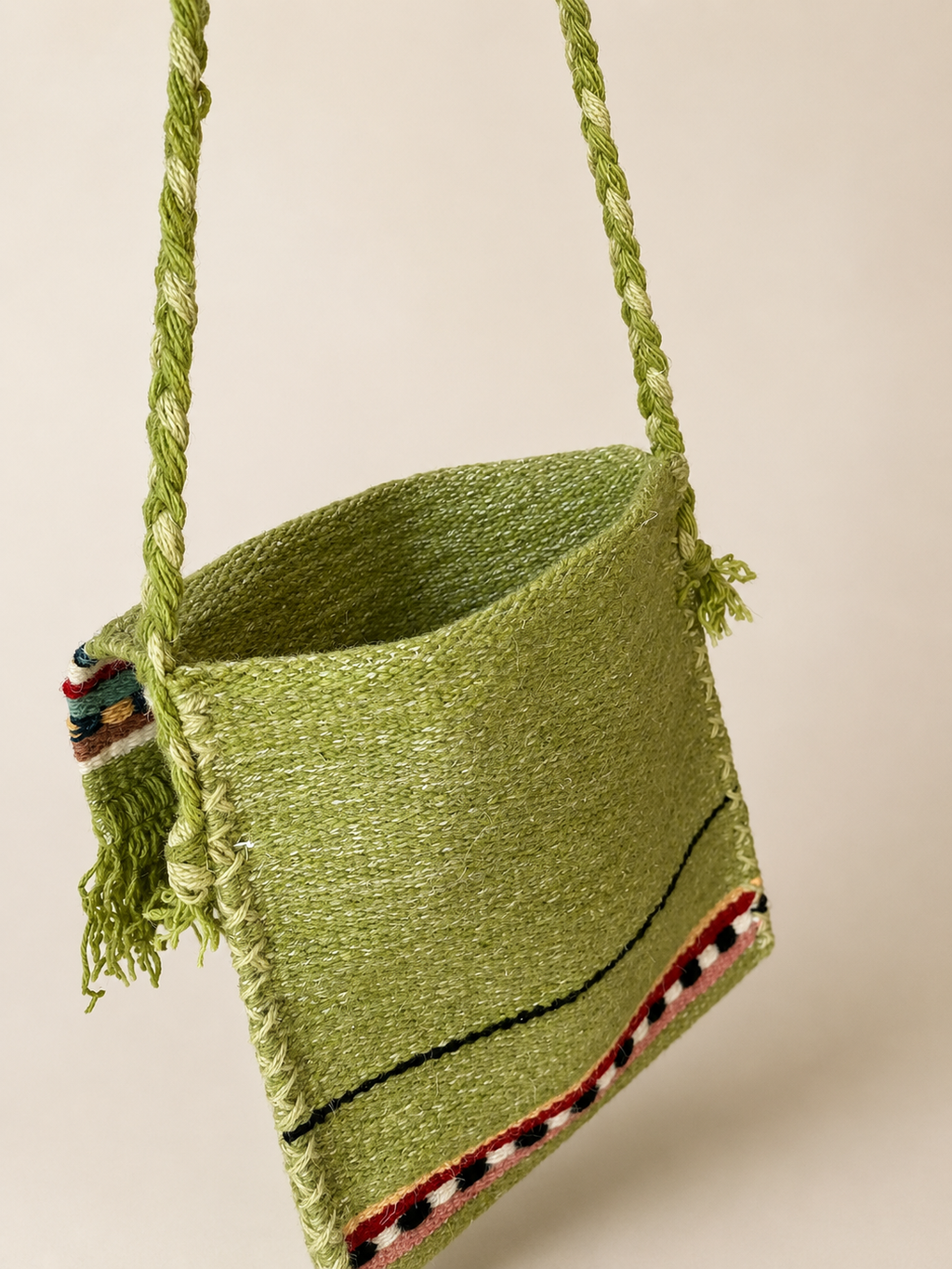 Green woven bag with tassels on a beige background